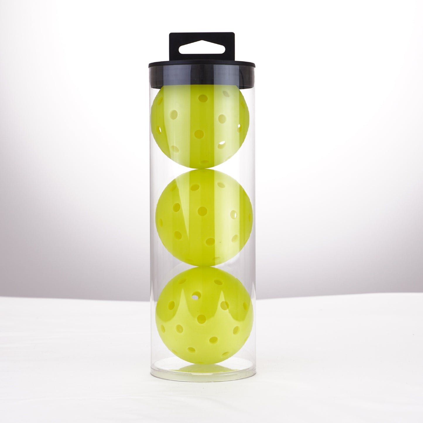 Three lime green 40-hole outdoor pickleballs in a clear tube, ready for tournament play.